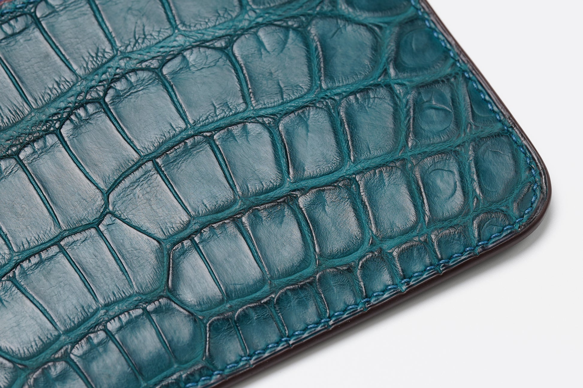 Macro detail of colvert crocodile leather texture and corner stitching