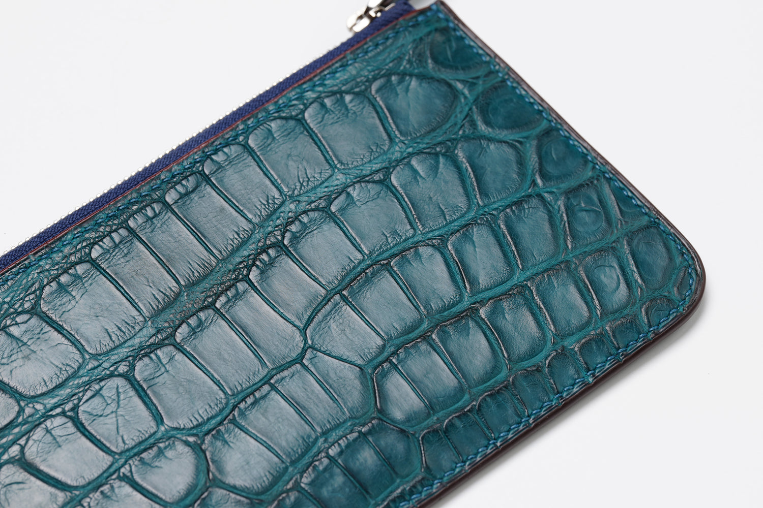 Macro view of edge stitching on colvert crocodile leather wallet